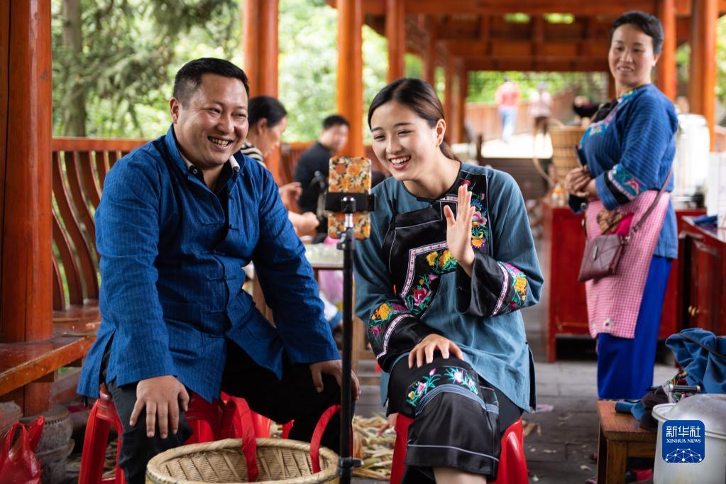 在湖南湘西十八洞村,十八洞村扶贫队长麻辉煌(左)与返乡大学生施林娇(中)一起直播推销土特产(2020年5月15日摄)。新华社记者 陈思汗 摄